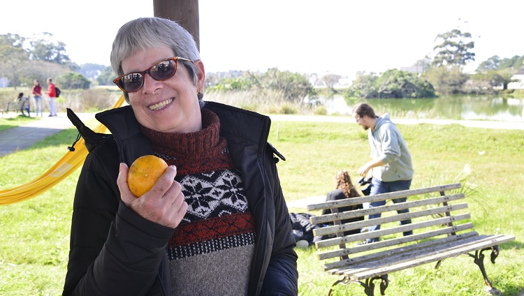 Mulher segurando bergamota na mão e sorrindo