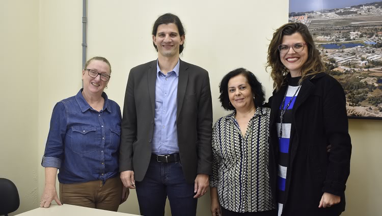 A imagem mostra quatro pessoas. Todas olham para a câmera e sorriem. À esquerda, uma mulher, ao lado dela o vice-reitor Danilo Giroldo e, ainda, ao lado direito da imagem, duas mulheres. 