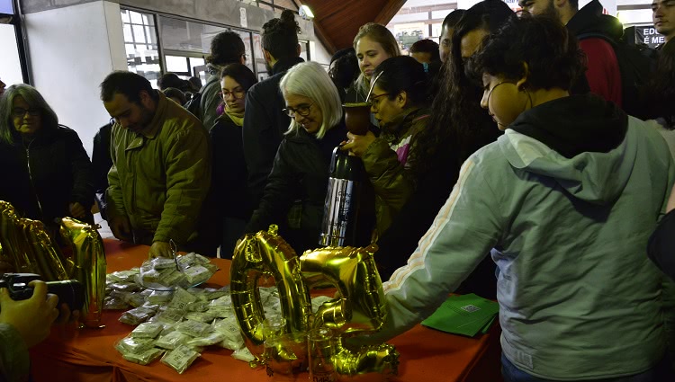 A imagem mostra estudantes retirando as palhas italianas distribuídas em uma mesa no CC