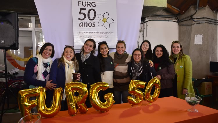 A imagem mostra pessoas na frente de uma mesa com balões comemorativos