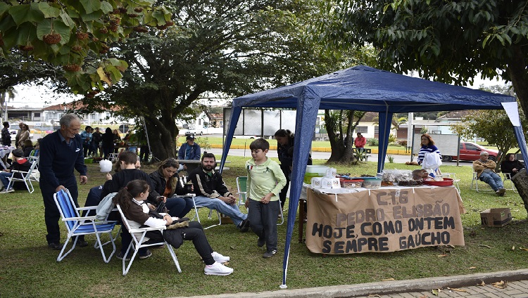 A imagem mostra uma tenda no meio da praça com produtos de artesanato expostos para a venda.