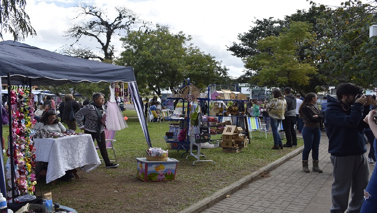 A imagem mostra tendas com produtos em exposição na praça.