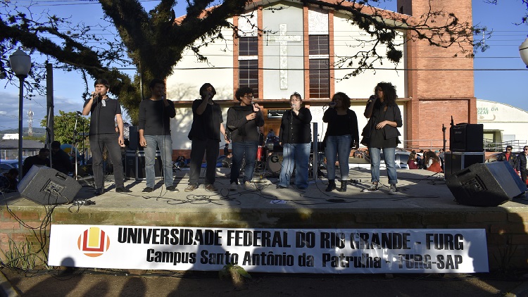 A foto mostra diversas pessoas em cima do palco discursando.