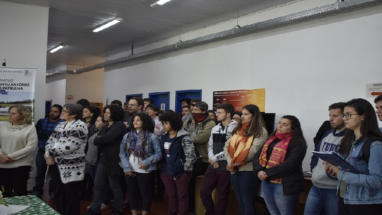 A imagem mostra diversas pessoas em pé no entorno da mesa.