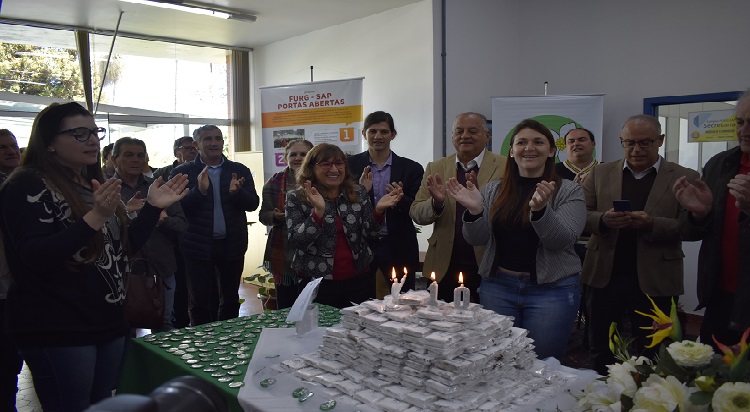 A imagem mostra diversas pessoas em pé no entorno da mesa.