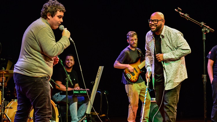 O estudante Fernando Neto no palco segurando o microfone e ao lado dele o cantor Vagnotreta