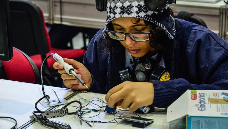 Imagem mostra estudante realizando ajustes em seu robô