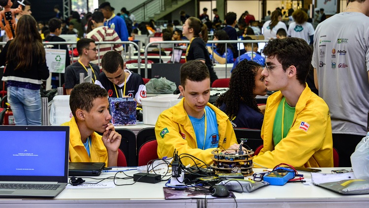 Imagem mostra competidores realizando ajustes em seus robôs