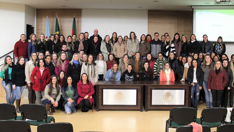 A imagem mostra um grande grupo de pessoas em um auditório, posicionados posando para a foto. 