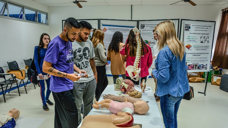 Imagem mostra estudantes da universidade apresentando equipamentos de laboratório