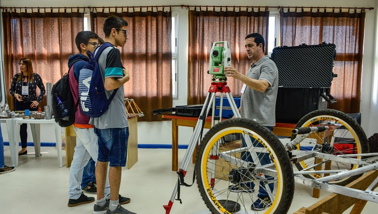 Imagem mostra estudantes da universidade apresentando equipamentos de laboratório