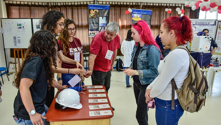 Imagem mostra visitantes conversando com estudantes apresentadores