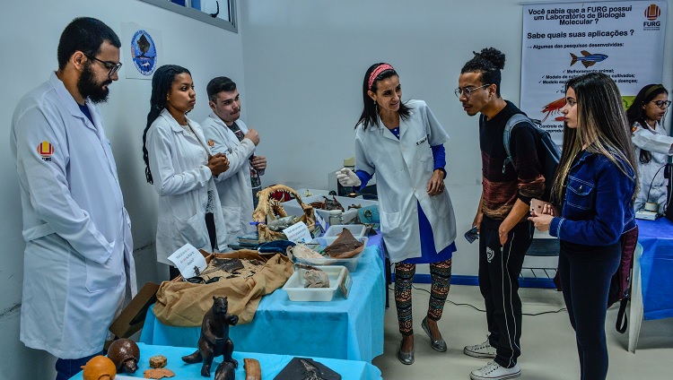 Imagem mostra estudantes da universidade apresentando equipamentos de laboratório