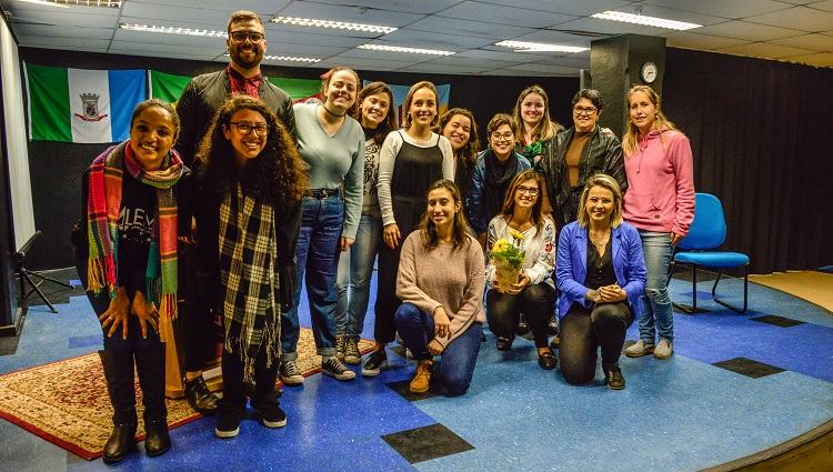 A foto mostra um grupo de pessoas reunidas lado a lado, umas estão agachadas e outras em pé.