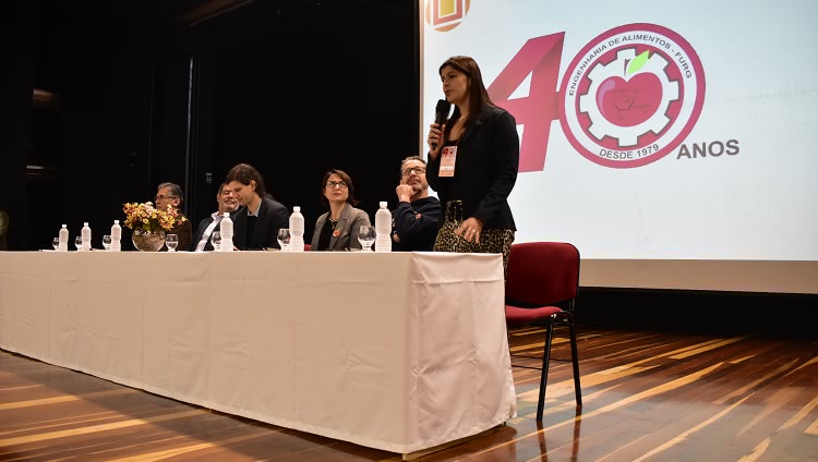 Imagem mostra pessoas compondo a mesa de abertura do evento