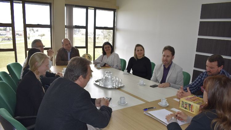 Imagem mostra mesa de reunião com diversas pessoas sentadas a sua volta