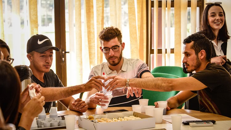 Imagem destaca três estudantes internacionais em momento de confraternização