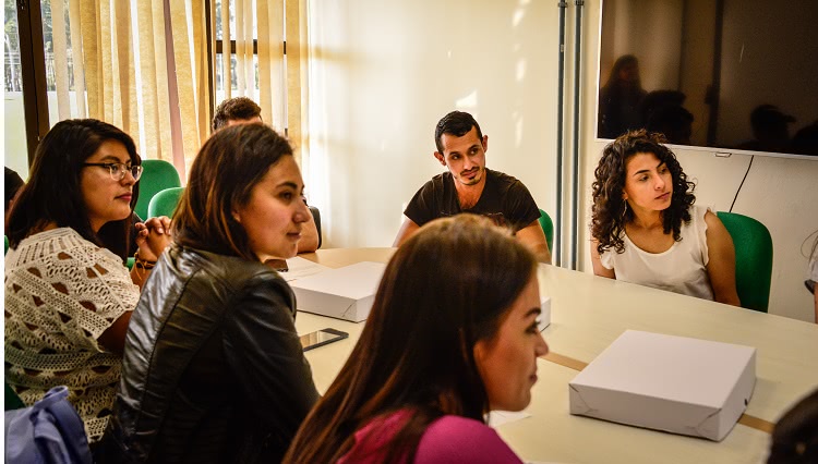 Imagem mostra estudantes reunidos ao redor de uma mesa