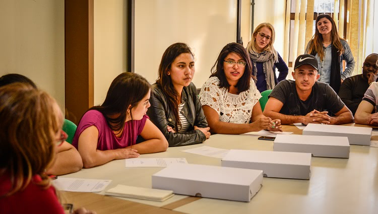 Imagem mostra estudantes internacionais ao redor de uma mesa