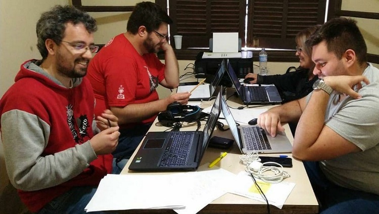 Quatro pessoas sentadas mexendo em computadores