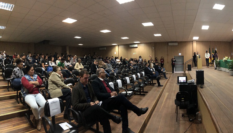 Plateia do evento sentada em fileiras de cadeiras