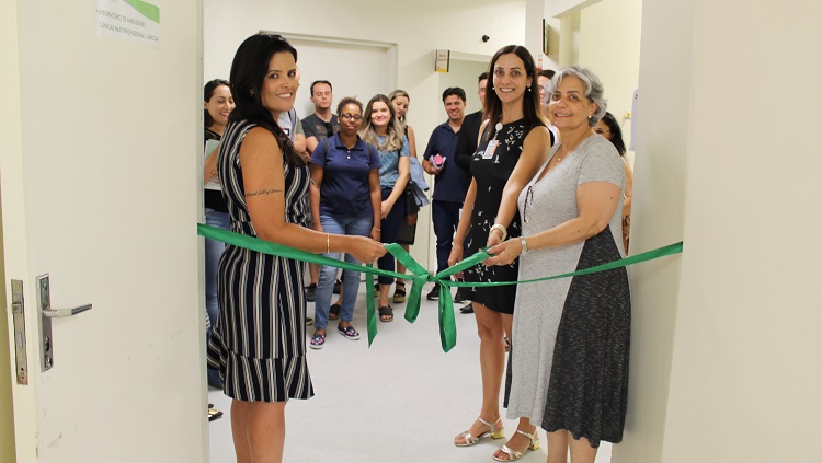 Duas mulheres cortam uma fita verde simbolizando a inauguração do espaço